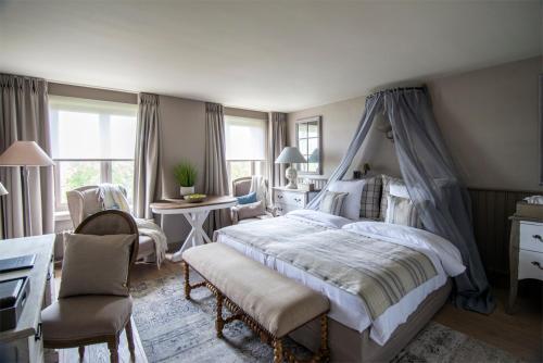 a bedroom with a canopy bed and a desk and chairs at Lebeaubylivingroom Hotel in Knokke-Heist