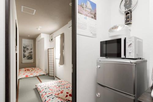 a small kitchen with a refrigerator and a bedroom at Osaka Nakayama Guesthouse in Osaka