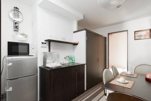 a small kitchen with a table and a refrigerator at Osaka Nakayama Guesthouse in Osaka