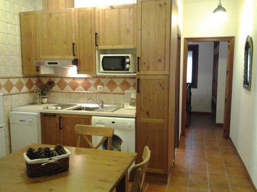 una cocina con armarios de madera, mesa y fregadero en Casa Rural Aya II, en Linares de la Sierra