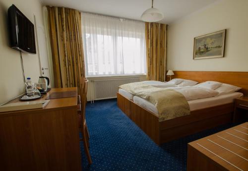 ein Hotelzimmer mit einem Bett und einem TV in der Unterkunft Hotel König-Stuben in Bispingen