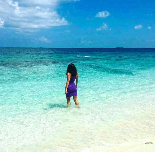 a young girl standing in the water on a beach at Aveyla Manta Village in Dharavandhoo