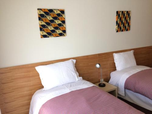 ヴィラ・ド・コンデにあるApartamento Praia Azulのベッドルーム1室(ベッド2台、テーブルの上にランプ付)