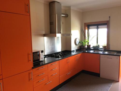 a kitchen with orange cabinets and a stove top oven at Apartamento Praia Azul in Vila do Conde