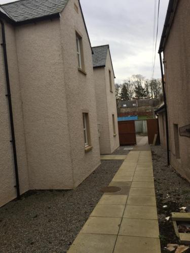an alley between two buildings with a sidewalk at 6 Varis Apartments in Forres