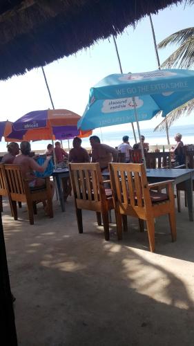a group of people sitting at tables with umbrellas on the beach at Leybato Beach Hotel in Fajara
