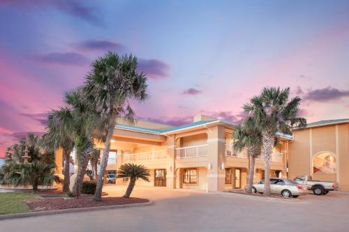 a building with palm trees in front of it at Super 8 by Wyndham Corpus Christi in Corpus Christi