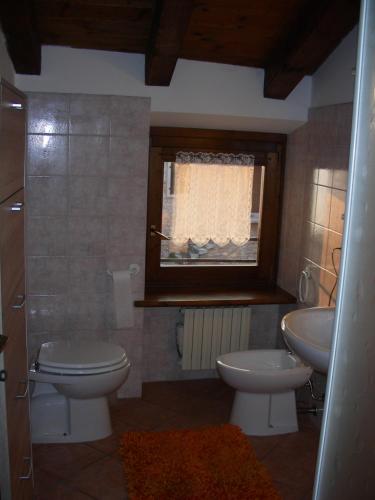 a bathroom with a toilet and a sink and a window at Casa Nadia in San Zeno di Montagna