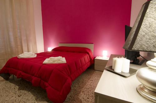 een slaapkamer met een rood bed en een roze muur bij Efesto Bed & Breakfast in Catania