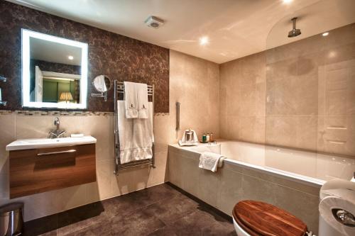 a bathroom with a tub and a sink and a toilet at Swinton Park in Masham