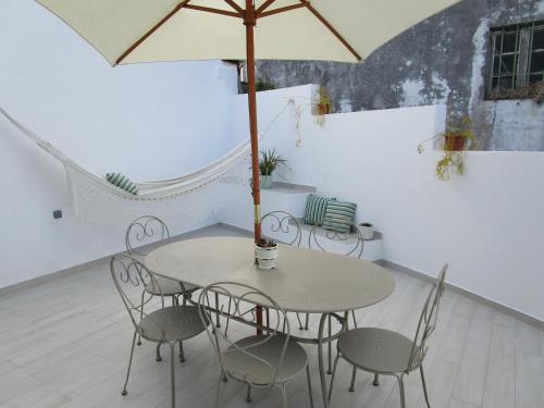 a table and chairs with an umbrella in a room at Casa Flor d'Sal in Angra do Heroísmo