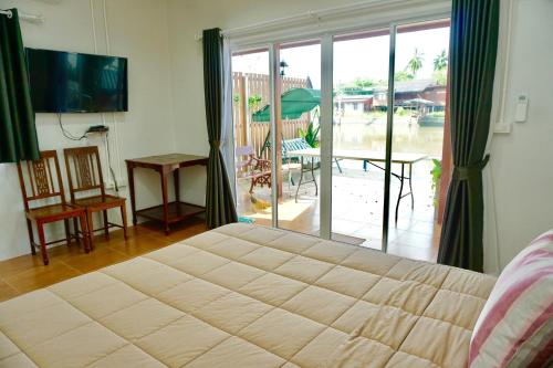 a bedroom with a large bed and a sliding glass door at Bansuwan Homestay in Amphawa