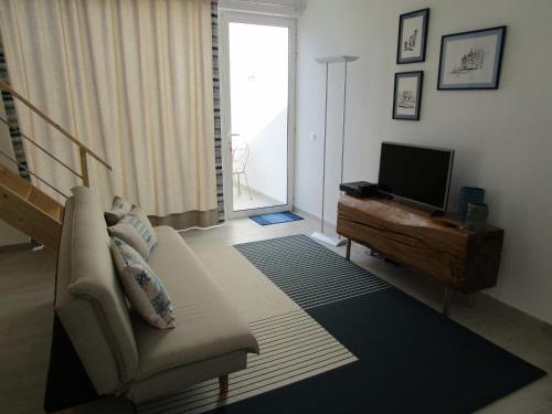 a living room with a couch and a television at Casa Flor d'Sal in Angra do Heroísmo