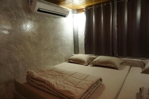 a bedroom with a bed and a window with a air conditioner at Bansuwan Homestay in Amphawa