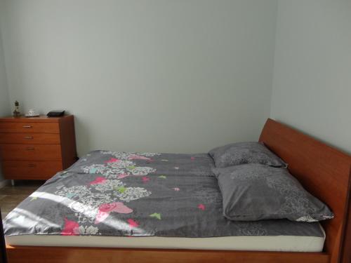 a bed with a gray comforter and pillows on it at Apartament Jelitkowski in Gdańsk