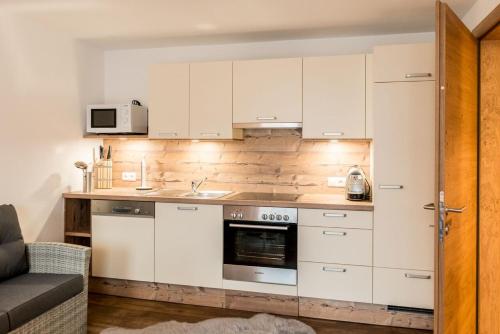 a kitchen with white cabinets and a stove top oven at Appartements Kolberhof in Alpbach