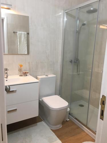 a bathroom with a toilet and a glass shower at Apartamento Praia Da Gaivota in Quarteira