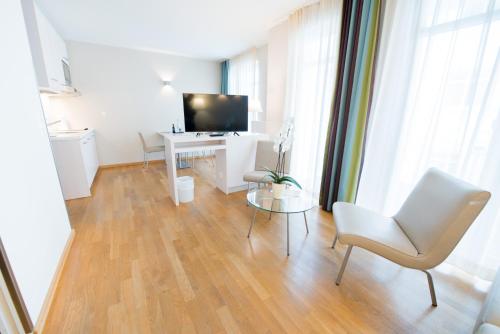 a living room with a television and a table and chairs at Nymphe Strandhotel & Apartments in Binz