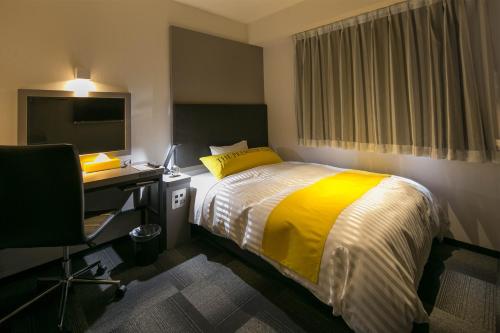 a bedroom with a bed and a desk and a television at Miyakonojo Green Hotel in Miyakonozyō