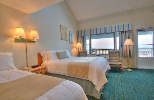 a hotel room with two beds and a chair at Terrace By The Sea in Ogunquit