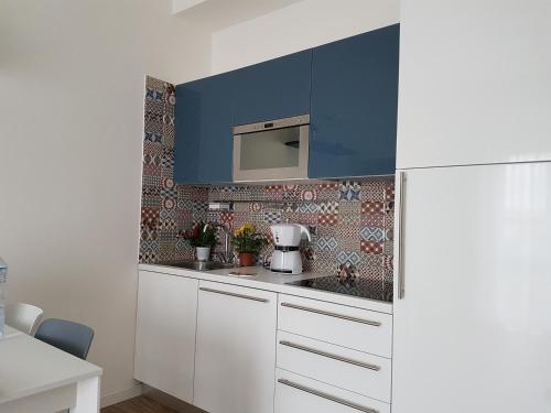 una cocina con armarios blancos y una pared azul en Suite Home Sophie, en Verona