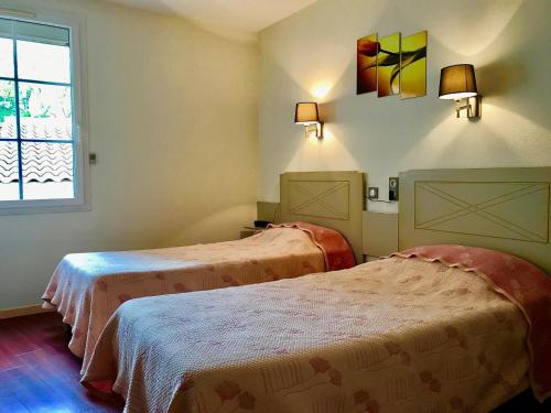 a room with two beds and a window at Logis Hotel Restaurant de la Montagne Noire in Dourgne