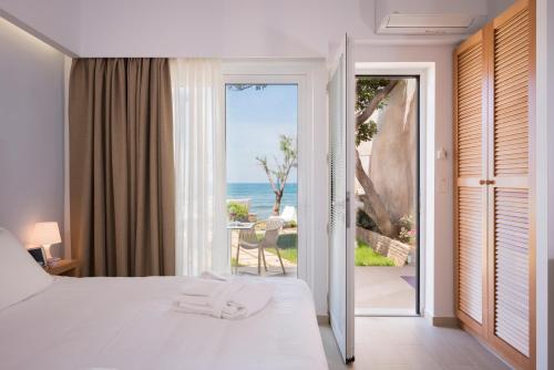 a bedroom with a bed and a view of the ocean at Hermes Beach Front in Stalos