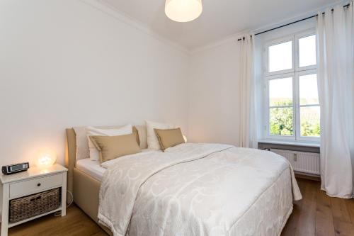 a white bedroom with a bed and a window at Gästehaus Sektstuuf St. Laurentius in Leiwen