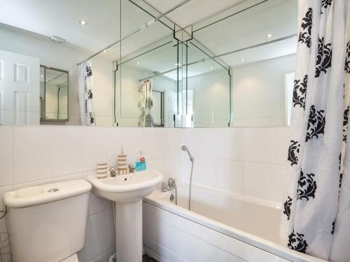 a white bathroom with a sink and a tub and a mirror at My-Places Abbotsfield Court Townhouse in Manchester