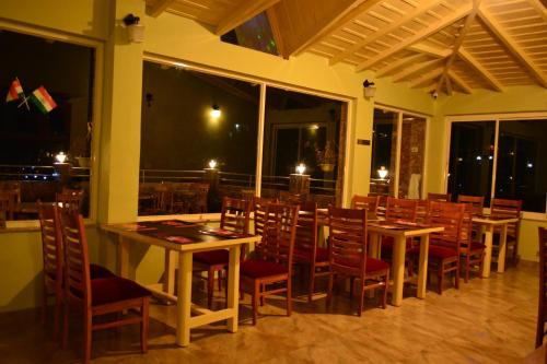 a dining room with tables and chairs and windows at The Golden Peak, Hotel in Mukteswar