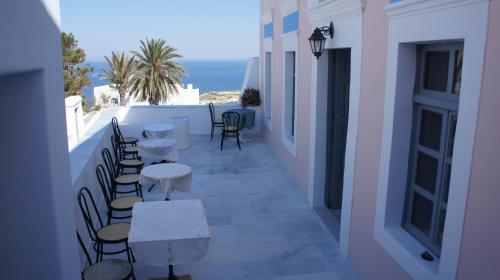 Un balcón con mesas y sillas y vistas al océano. en Marcos Rooms, en Oia