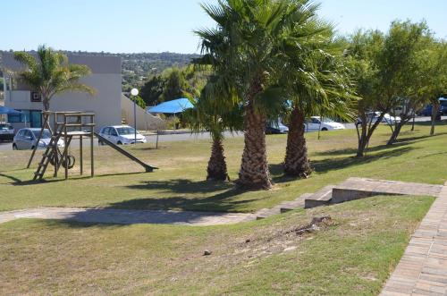 a park with palm trees and a swing set at Villa De Vie Self Catering Apartment in Brackenfell