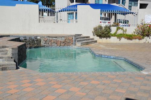 a swimming pool with a stone retaining wall and a stonenergynergynergyploadpload at Villa De Vie Self Catering Apartment in Brackenfell