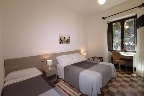 a hotel room with two beds and a desk and a desk at Villa Astoria in Taormina