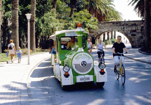 a green and white trolly car with people riding bikes at Cosmopolitan Hotel in Kos Town