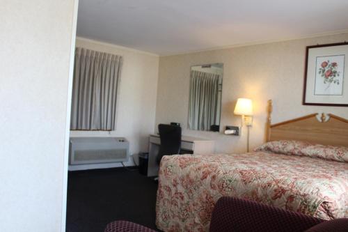 ウェストフィールドにあるElm Motelのベッド、デスク、バスタブが備わるホテルルームです。