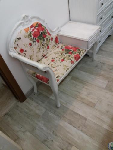 a white chair with a floral seat next to a dresser at For Ever Apartments in Fiumicino