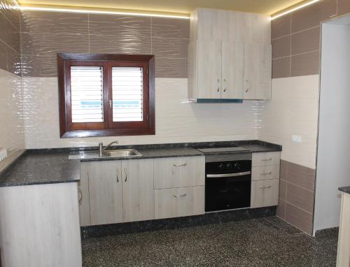 a kitchen with white cabinets and a sink and a window at Can Mossènyer in San Antonio