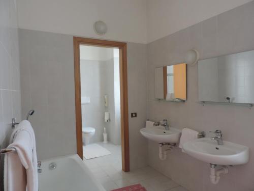 a white bathroom with two sinks and a mirror at Hotel Vapore in Torno