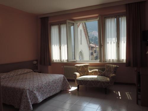 een slaapkamer met een bed, een stoel en een raam bij Hotel Vapore in Torno