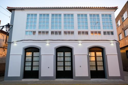 a white building with four windows on it at Pensión Domus Gallery in Arzúa
