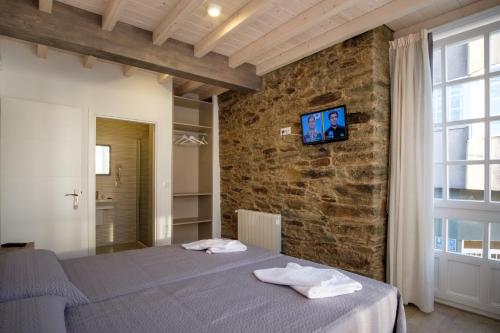 a bedroom with a bed and a brick wall at Pensión Domus Gallery in Arzúa