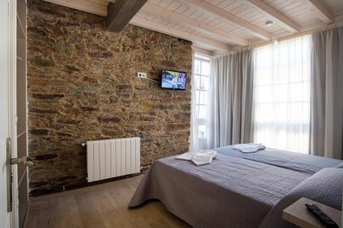 a bedroom with a bed and a brick wall at Pensión Domus Gallery in Arzúa