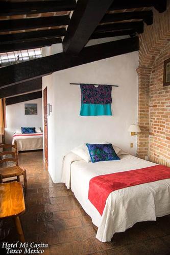a bedroom with two beds and a brick wall at Hotel Mi Casita in Taxco de Alarcón