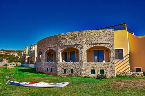 a building with a boat on the grass in front of it at Element Hotel in Elafonisos