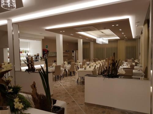 un comedor con mesas blancas y sillas blancas en Hotel Solemare, en Cesenatico