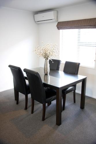 a dining room table with chairs and a vase with flowers at Camelot On Ulster in Hamilton