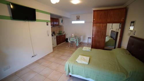 a bedroom with a green bed and a kitchen at Departamentos Rodrigo in Posadas