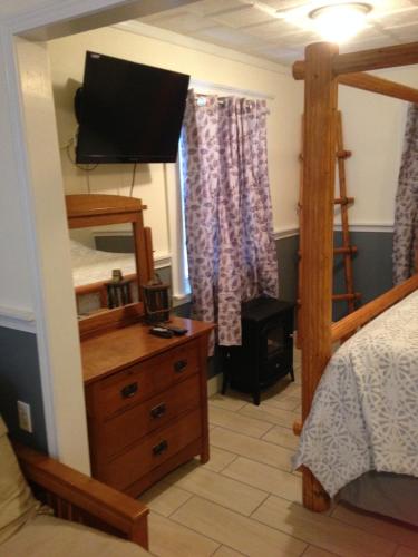 a bedroom with a bed and a dresser with a television at Foster Lake Inn in Sweet Home