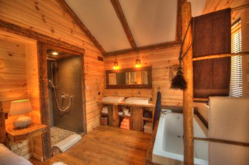 Baño en una cabaña de madera con bañera y lavamanos en Le St Bernard - Les Chalets Spa Canada, en La Malbaie